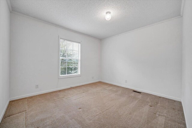 carpeted empty room with baseboards, visible vents, a textured ceiling, and ornamental molding