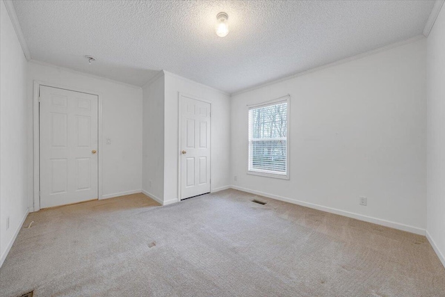 unfurnished bedroom featuring visible vents, ornamental molding, and carpet