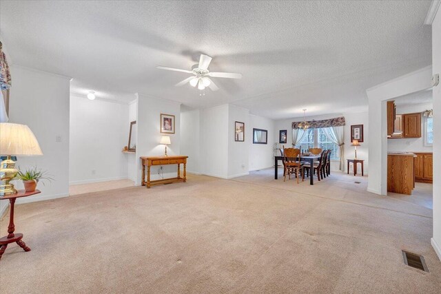 living room featuring visible vents, a ceiling fan, light colored carpet, and a textured ceiling
