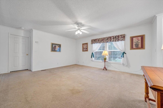 spare room with visible vents, a ceiling fan, a textured ceiling, crown molding, and light colored carpet