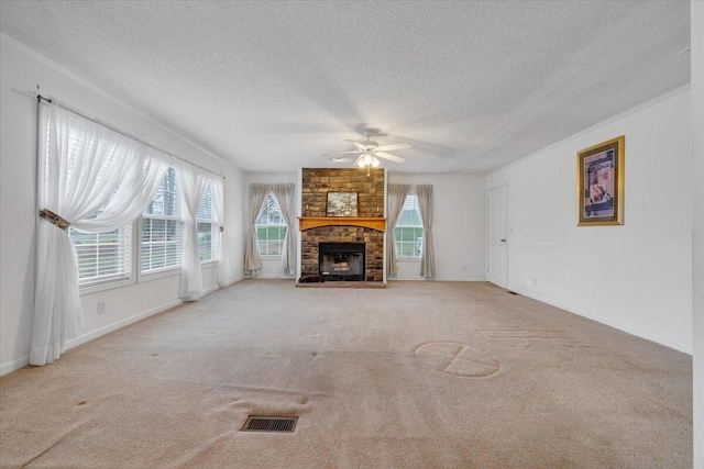 unfurnished living room with baseboards, a fireplace, visible vents, ceiling fan, and carpet