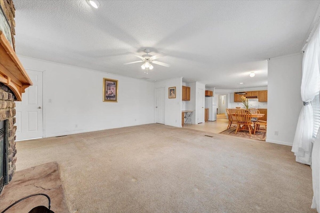 unfurnished living room with light carpet, a stone fireplace, a ceiling fan, and a textured ceiling