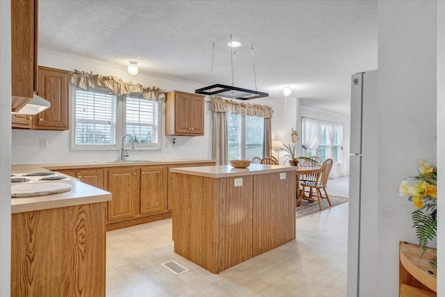 kitchen with a kitchen island, ventilation hood, a sink, and light floors