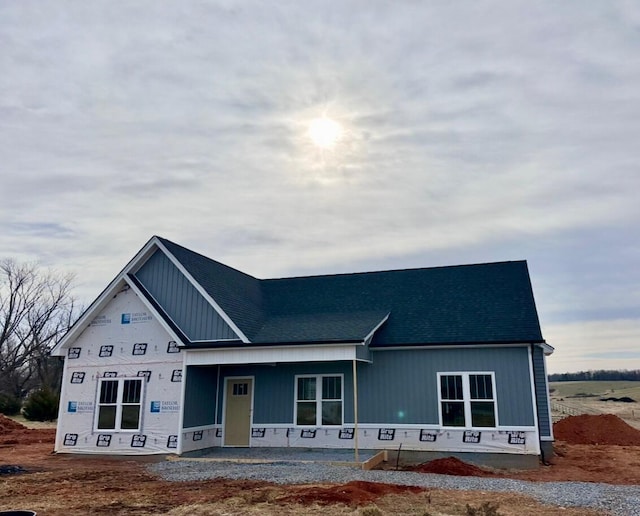 property under construction with a shingled roof and covered porch