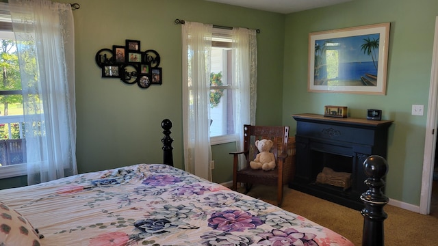 carpeted bedroom with a fireplace and baseboards