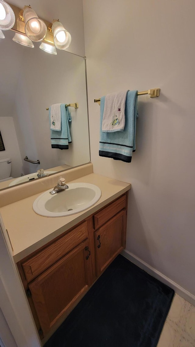 bathroom with toilet, vanity, and baseboards