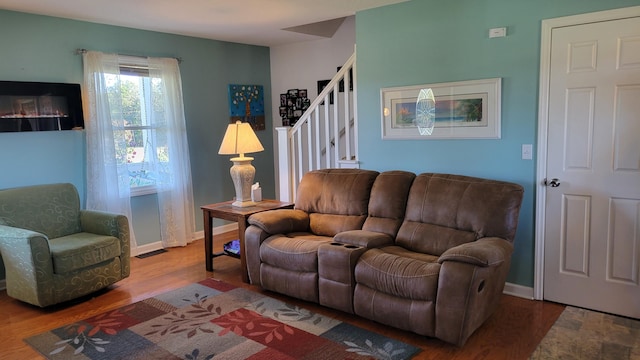 living area featuring baseboards, visible vents, stairway, and wood finished floors