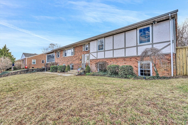 view of front facade with brick siding, a front yard, fence, and stucco siding