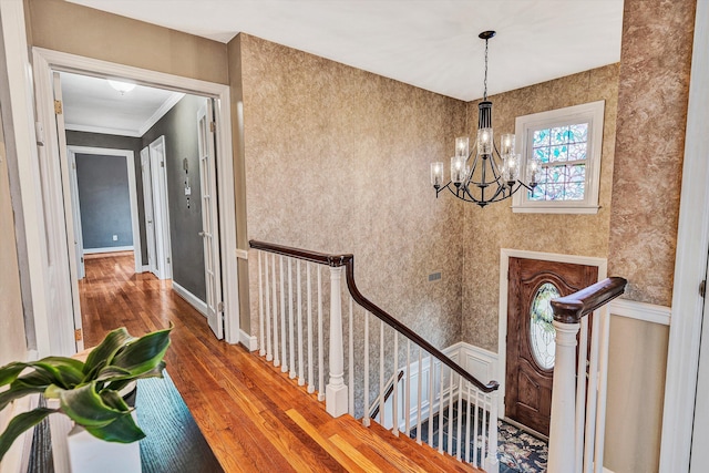 entryway with wallpapered walls, baseboards, a chandelier, and wood finished floors