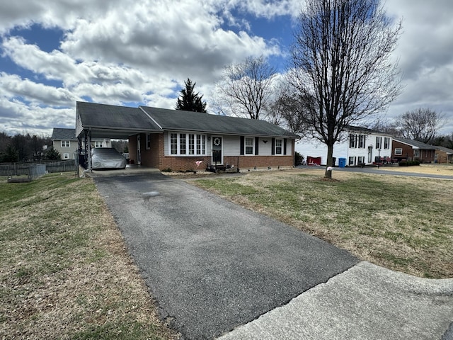 single story home featuring brick siding, fence, aphalt driveway, a front yard, and a carport