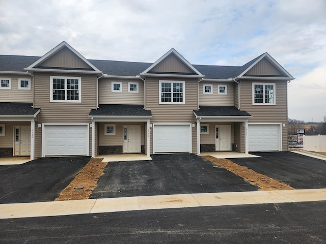 townhome / multi-family property featuring a garage, driveway, and a shingled roof