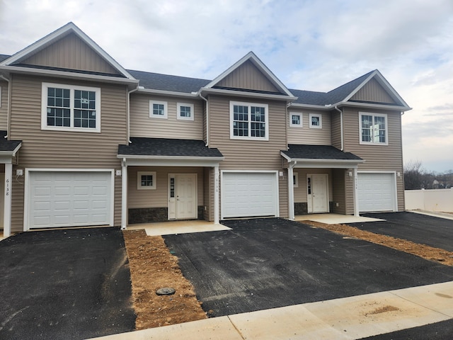 townhome / multi-family property featuring a garage, driveway, and a shingled roof