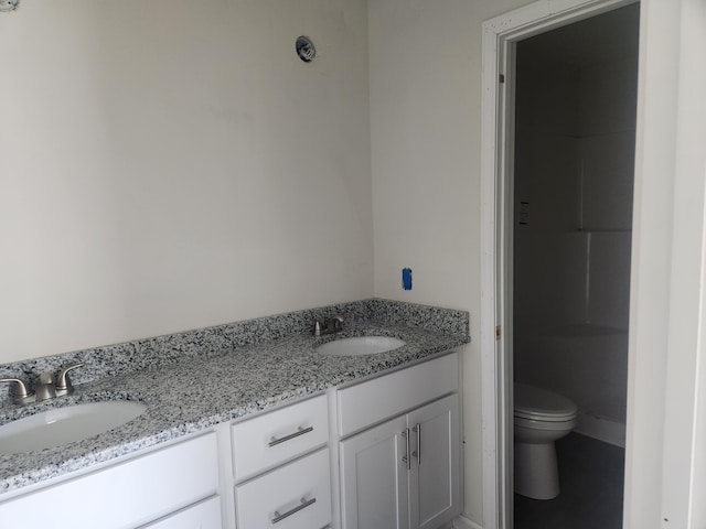 bathroom featuring double vanity, a sink, and toilet