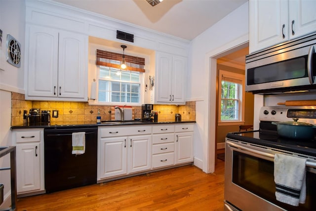 kitchen with appliances with stainless steel finishes, dark countertops, white cabinets, and a sink