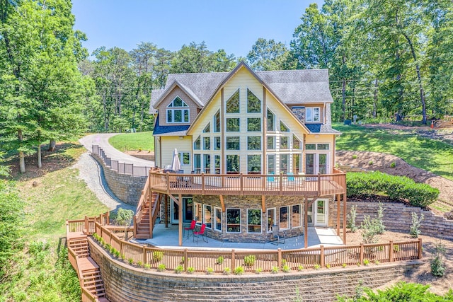 back of house with roof with shingles, a lawn, stairway, a patio area, and a wooden deck