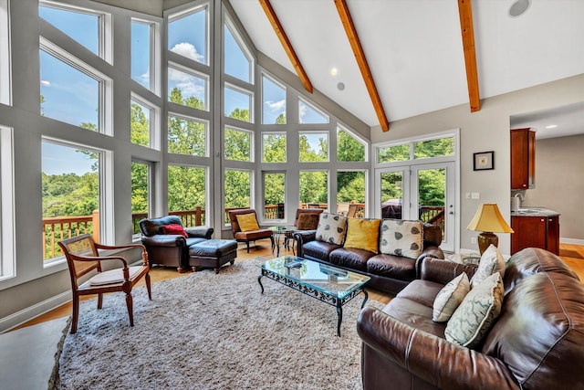 living area featuring high vaulted ceiling, beamed ceiling, baseboards, and wood finished floors