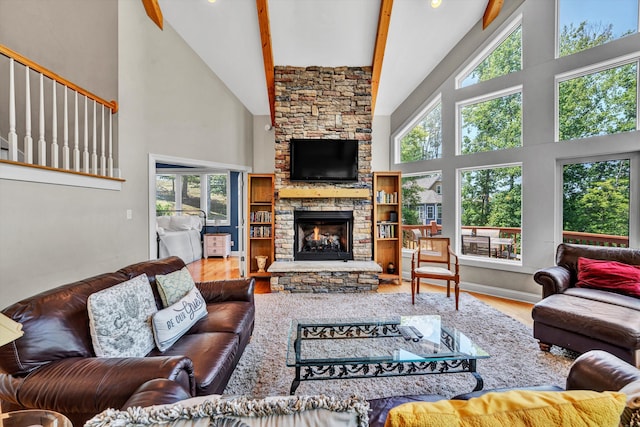 living room featuring high vaulted ceiling, a stone fireplace, beamed ceiling, and wood finished floors