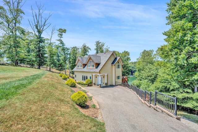 view of front of house featuring aphalt driveway, a front yard, and fence