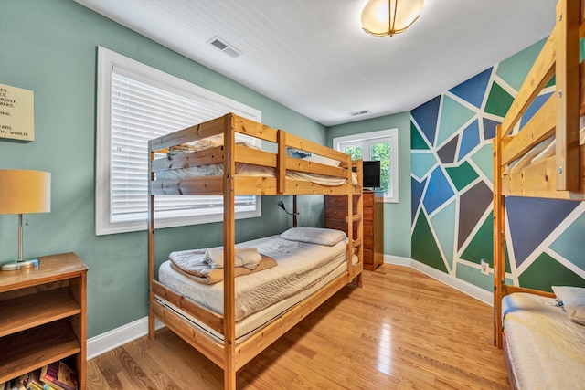 bedroom with wood finished floors, visible vents, and baseboards