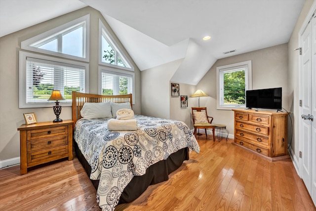 bedroom featuring light wood-style floors, baseboards, visible vents, and vaulted ceiling