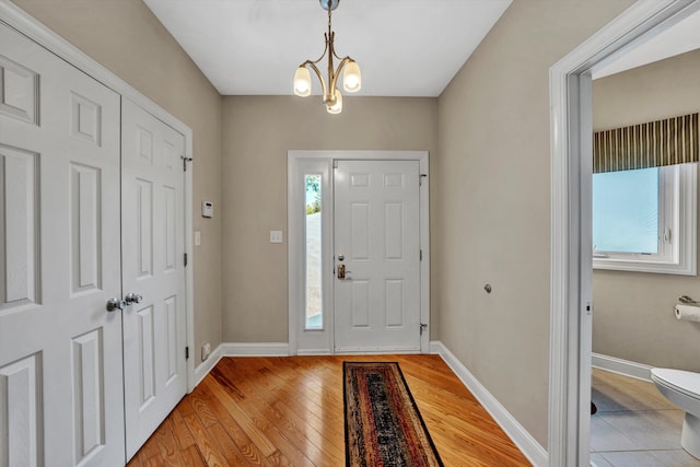 entryway with a chandelier, light wood-style flooring, and baseboards