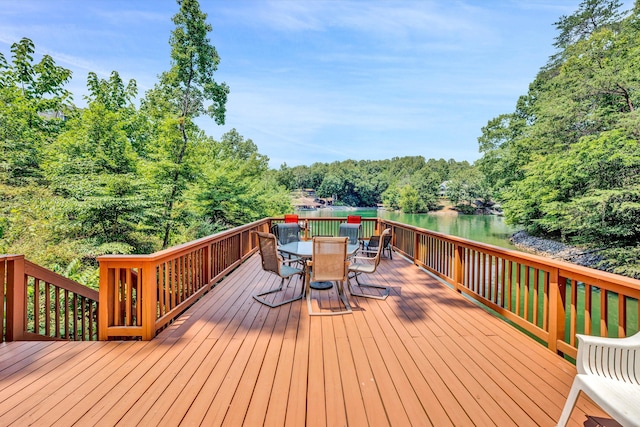 wooden terrace with a forest view, outdoor dining area, and a water view