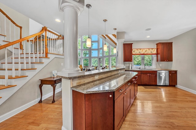 kitchen with stainless steel dishwasher, light wood-type flooring, a sink, and ornate columns