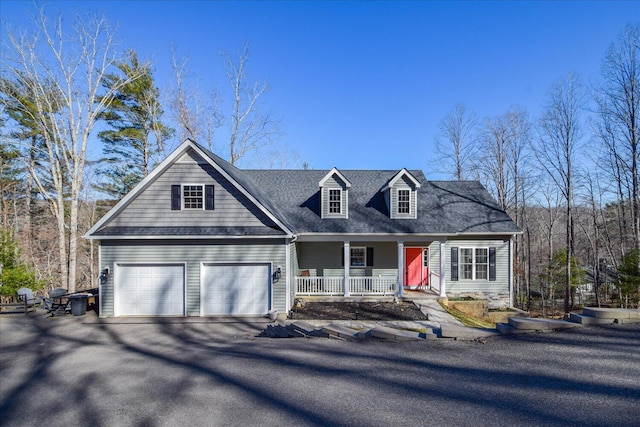 cape cod-style house featuring a garage, driveway, and a porch