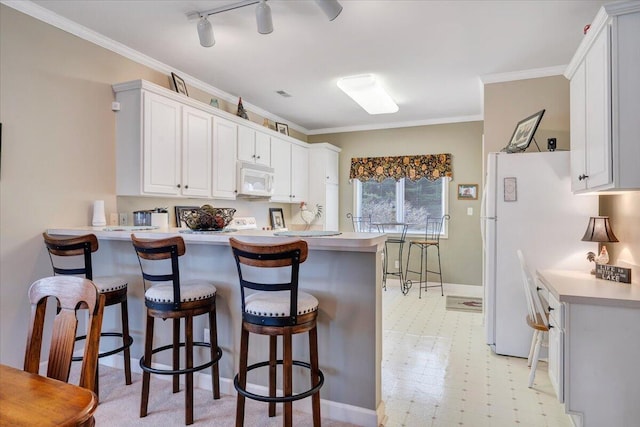 kitchen with white appliances, ornamental molding, a breakfast bar, a peninsula, and light floors