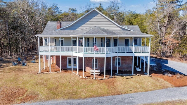 rear view of property with covered porch, a lawn, and a chimney