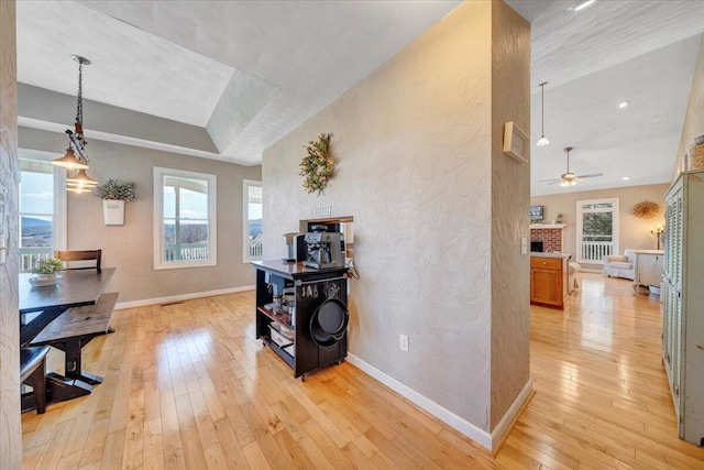 corridor featuring light wood-type flooring, visible vents, baseboards, and a textured wall