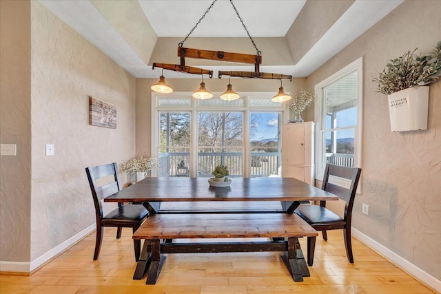 dining room with a textured wall, light wood-type flooring, and baseboards