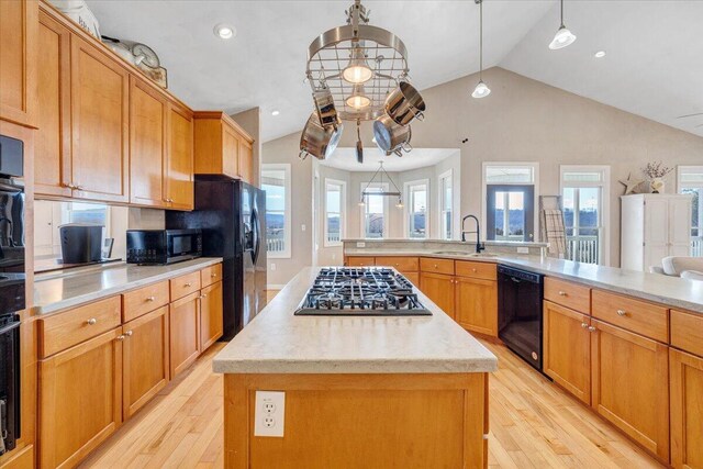 kitchen featuring black appliances, a wealth of natural light, a sink, and a center island