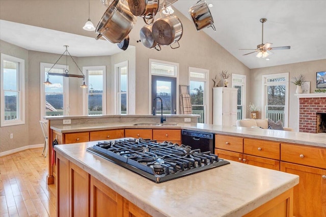 kitchen with black dishwasher, a center island, light countertops, stovetop, and a sink