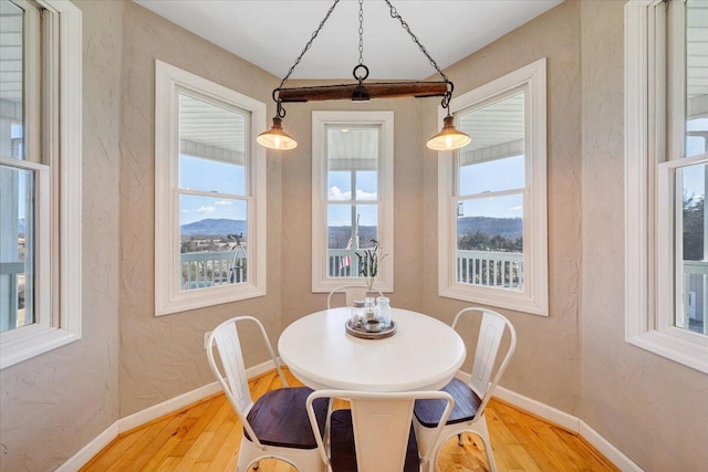 dining space with a textured wall, wood finished floors, and baseboards