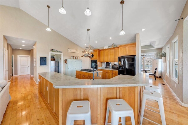 kitchen featuring a spacious island, light wood-style floors, black fridge, freestanding refrigerator, and pendant lighting