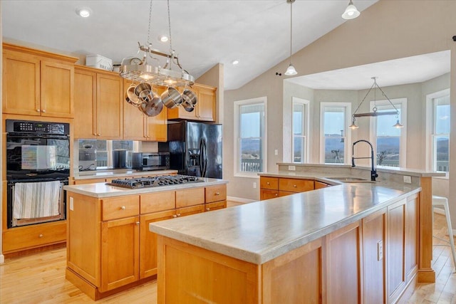 kitchen with black appliances, light wood-style floors, a spacious island, and a sink