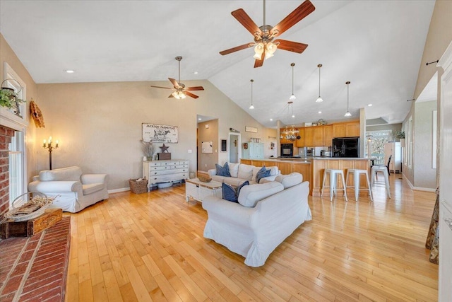 living area with high vaulted ceiling, light wood-type flooring, and baseboards