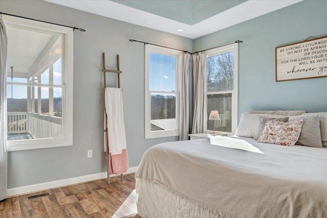 bedroom with visible vents, baseboards, and wood finished floors