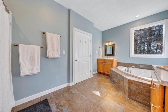 full bath with a garden tub, vanity, and baseboards