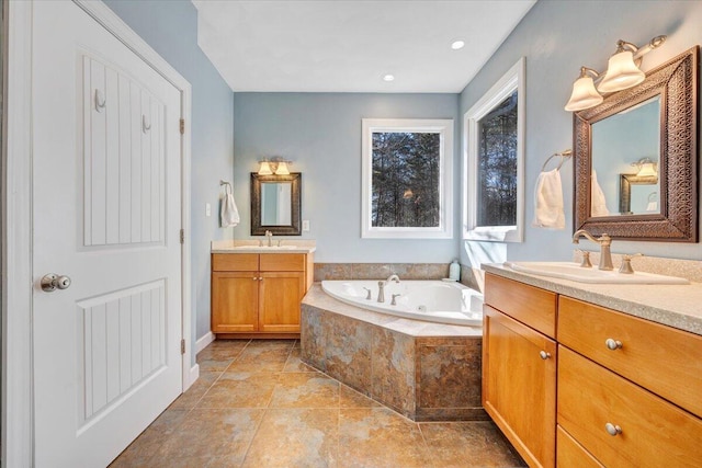 full bath featuring two vanities, a sink, and a bath