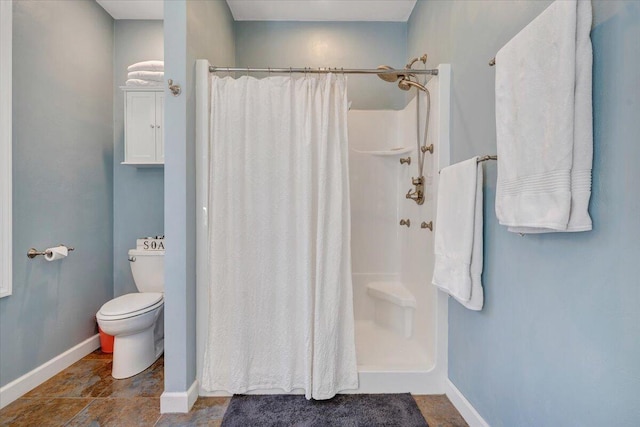 bathroom featuring toilet, baseboards, and a shower with shower curtain