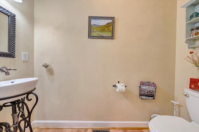 half bath with a sink, toilet, and baseboards