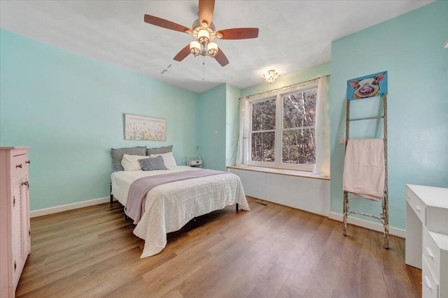 bedroom featuring ceiling fan, baseboards, and wood finished floors