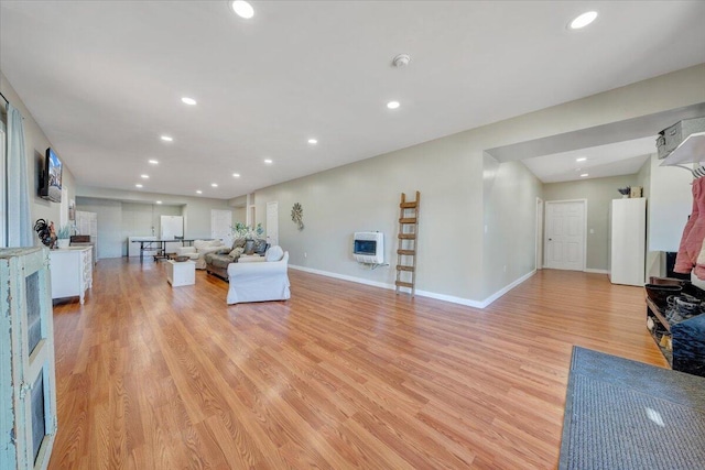 living room featuring baseboards, recessed lighting, heating unit, and light wood-style floors