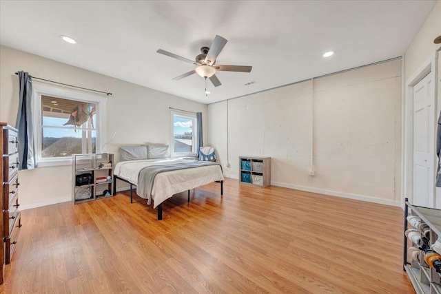 bedroom with light wood finished floors, multiple windows, and baseboards