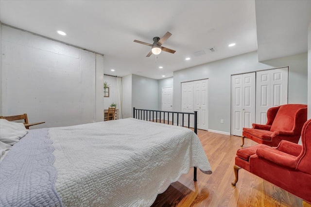 bedroom with light wood-type flooring, two closets, and recessed lighting