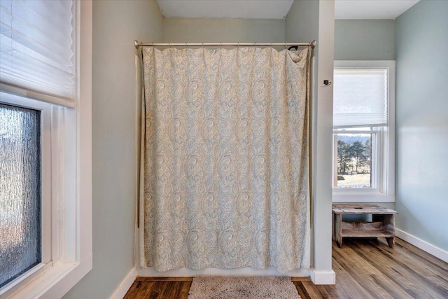 bathroom with curtained shower, wood finished floors, and baseboards