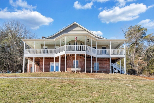 rear view of house featuring stairs, a yard, and brick siding