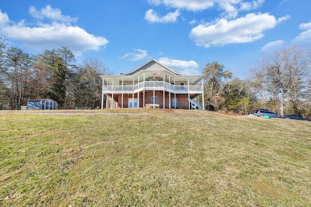 rear view of house featuring a storage shed, a lawn, an outbuilding, a deck, and brick siding